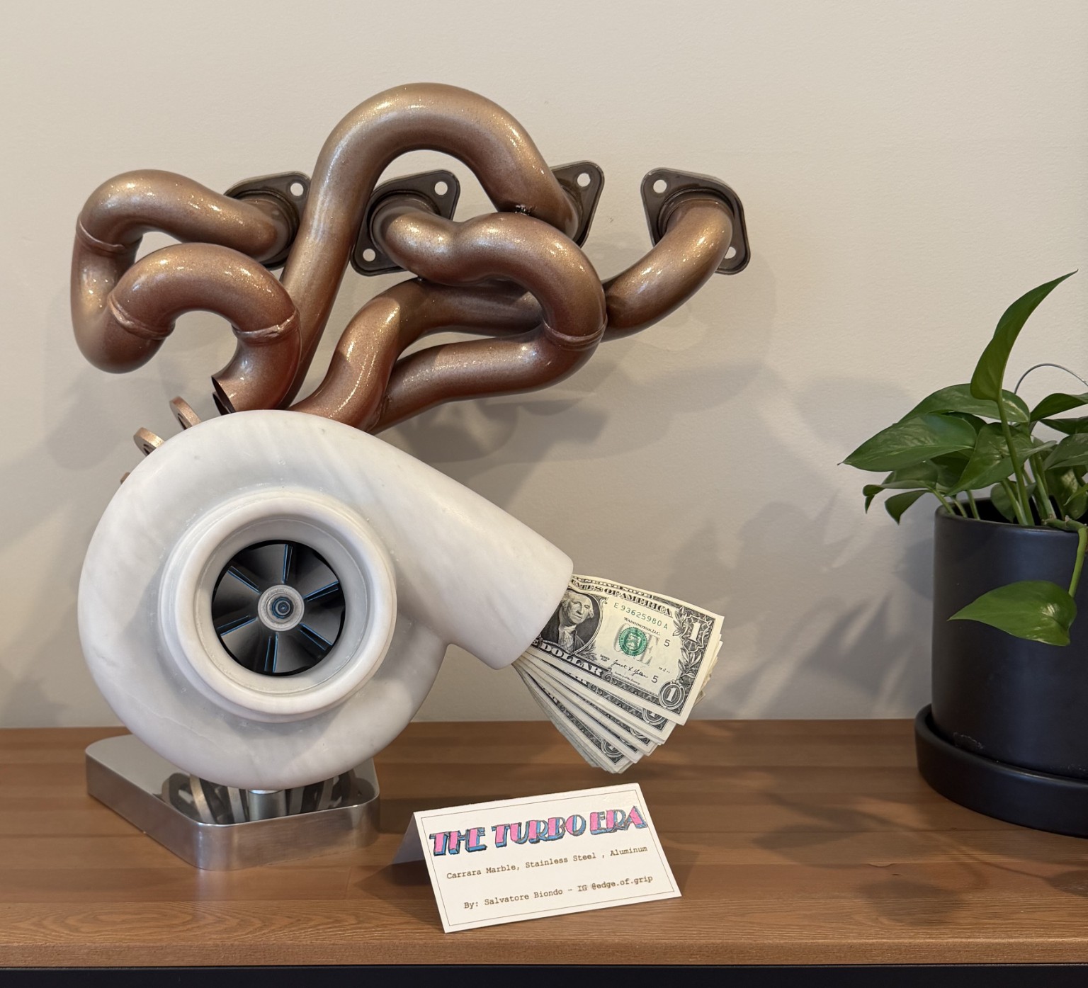 The Turbo Era sculpture: a marble turbocharger beneath an intricate metal exhaust manifold